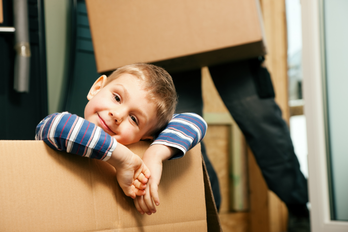 smiling child playing in box while moving into new home